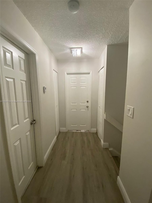 hall with dark wood-type flooring and a textured ceiling