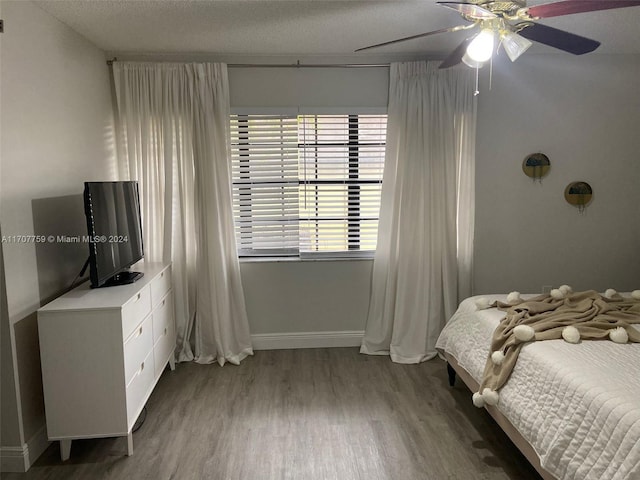 bedroom with ceiling fan, hardwood / wood-style floors, and a textured ceiling