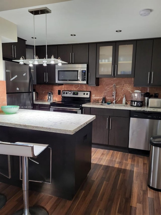 kitchen with dark hardwood / wood-style flooring, backsplash, stainless steel appliances, sink, and pendant lighting