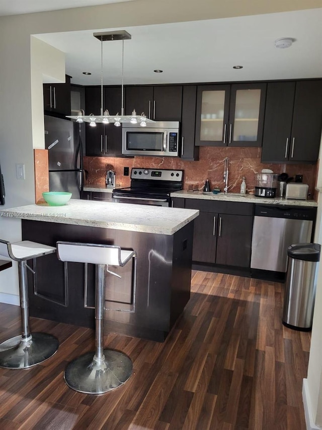 kitchen featuring sink, stainless steel appliances, tasteful backsplash, dark hardwood / wood-style floors, and pendant lighting