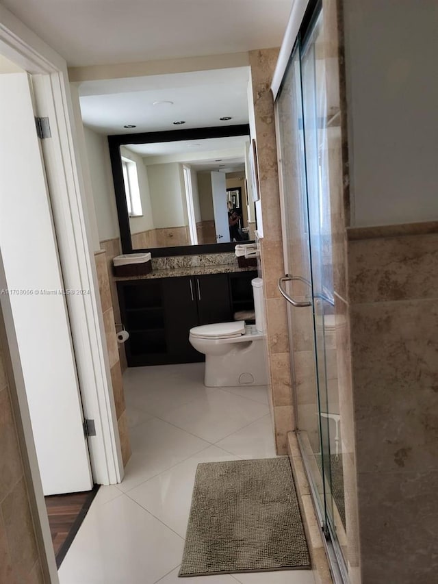 bathroom featuring tile patterned flooring, vanity, an enclosed shower, and toilet