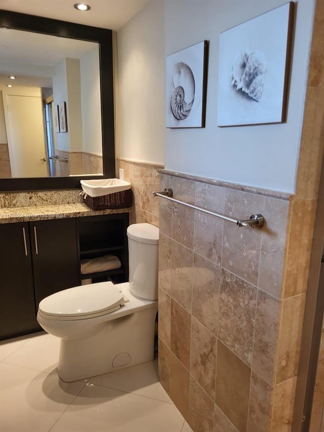 bathroom with tile patterned flooring, vanity, tile walls, and toilet