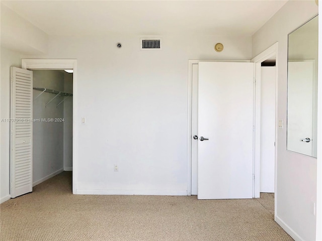 unfurnished bedroom featuring a walk in closet, light carpet, and a closet