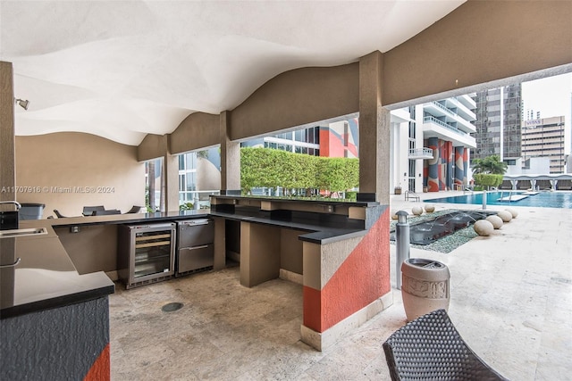 view of patio with area for grilling, a community pool, beverage cooler, and sink