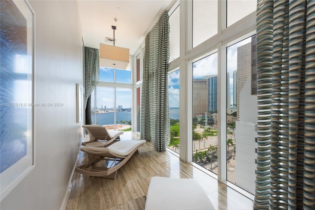 doorway with expansive windows, a healthy amount of sunlight, a water view, and light hardwood / wood-style floors