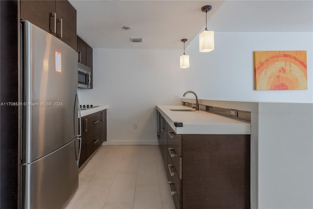 kitchen with sink, hanging light fixtures, light tile patterned flooring, dark brown cabinetry, and stainless steel appliances