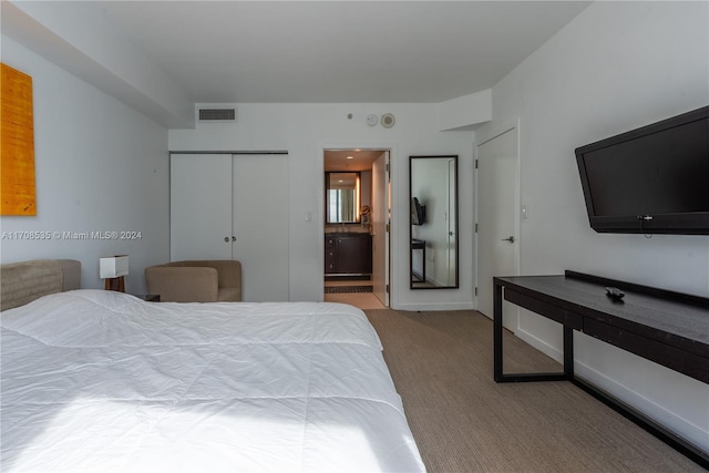 bedroom featuring ensuite bathroom, a closet, and light colored carpet