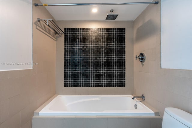 bathroom with tiled shower / bath combo and toilet