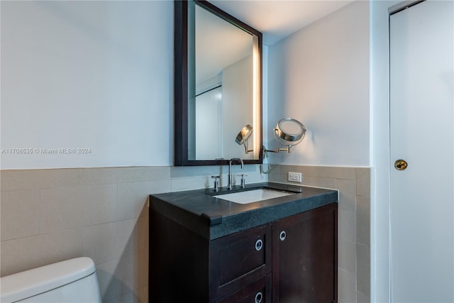 bathroom featuring vanity, toilet, and tile walls