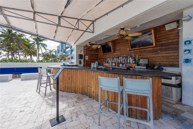 view of patio with ceiling fan and a bar