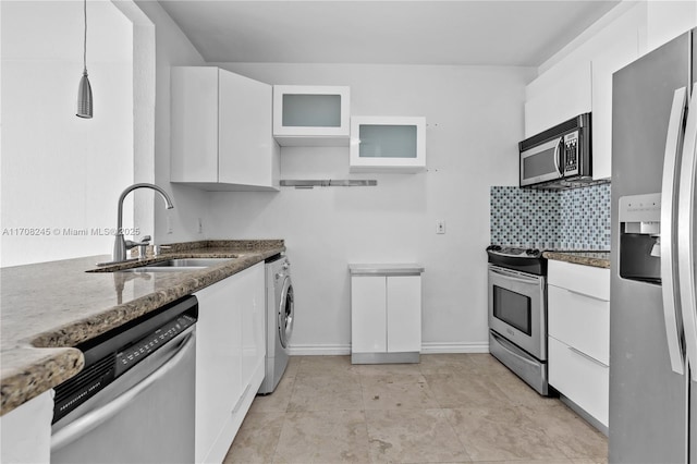 kitchen with pendant lighting, sink, appliances with stainless steel finishes, white cabinetry, and washer / dryer