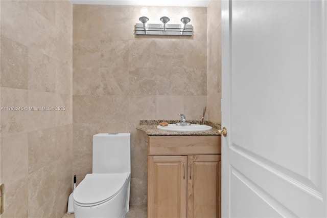 bathroom with vanity, toilet, and tile walls