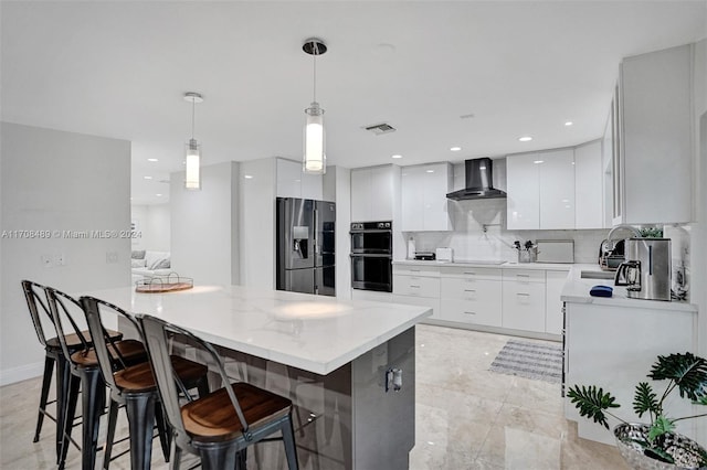 kitchen featuring stainless steel refrigerator with ice dispenser, wall chimney exhaust hood, decorative light fixtures, a kitchen island, and white cabinetry