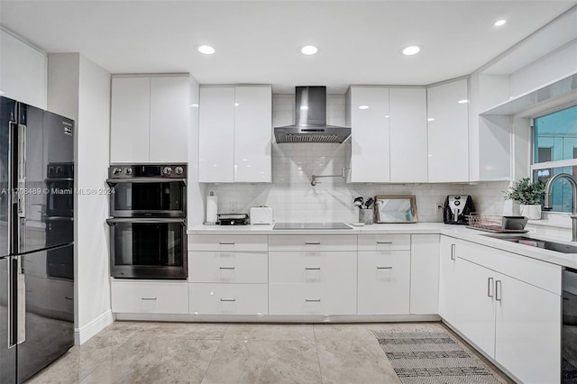 kitchen featuring tasteful backsplash, sink, black appliances, wall chimney range hood, and white cabinets