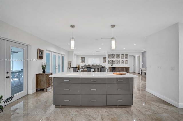 kitchen with gray cabinets, a kitchen island with sink, french doors, and pendant lighting