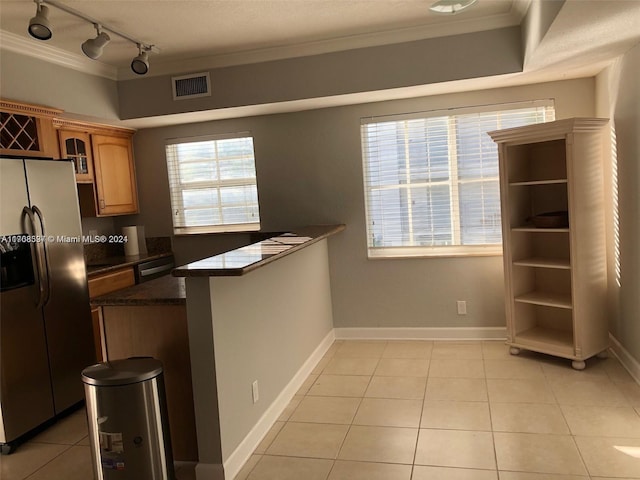 kitchen featuring dark stone counters, stainless steel refrigerator with ice dispenser, light tile patterned floors, ornamental molding, and kitchen peninsula