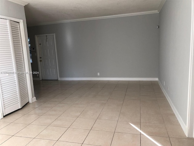 tiled spare room featuring crown molding