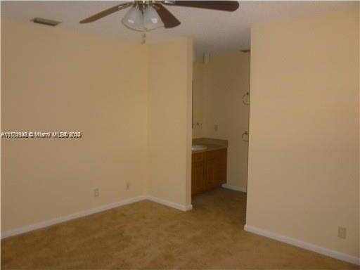 spare room featuring light carpet and ceiling fan