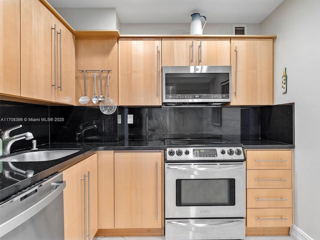 kitchen with light brown cabinetry, appliances with stainless steel finishes, sink, and decorative backsplash