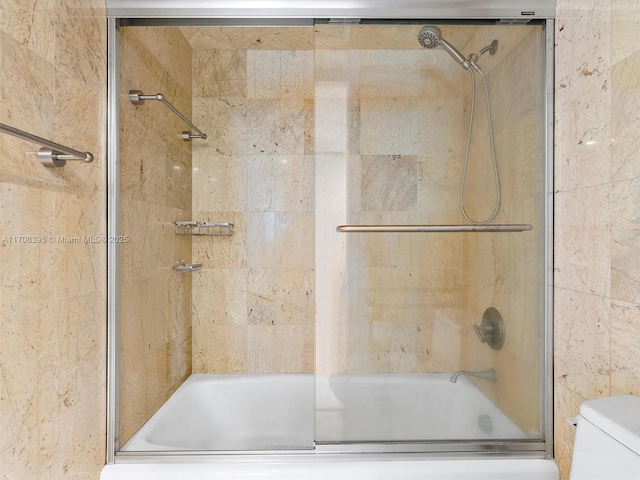 bathroom with shower / bath combination with glass door and toilet