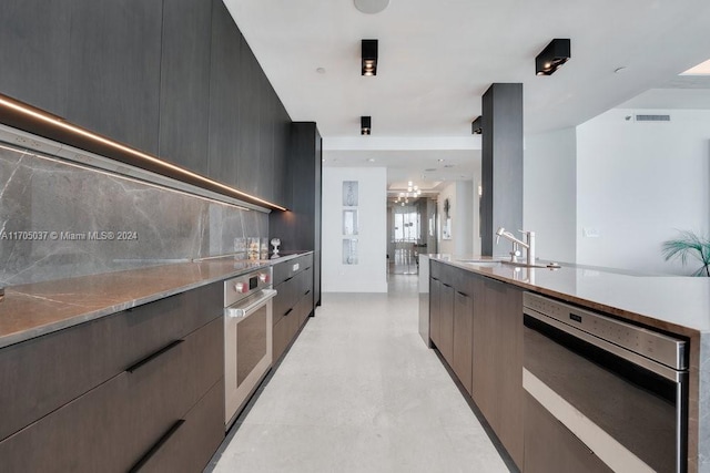 kitchen featuring oven, decorative backsplash, and sink