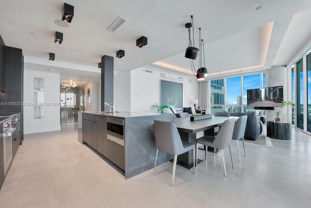 kitchen with pendant lighting, a raised ceiling, a spacious island, and sink