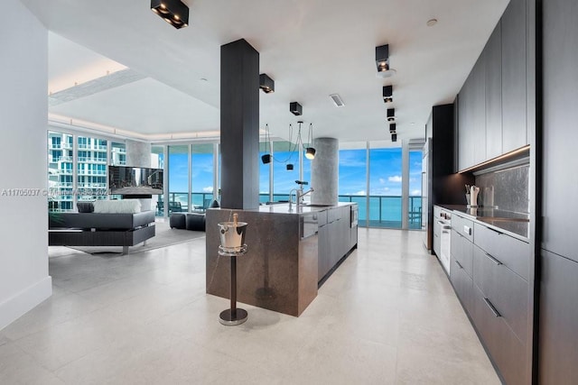 kitchen featuring a kitchen bar, backsplash, expansive windows, a spacious island, and sink