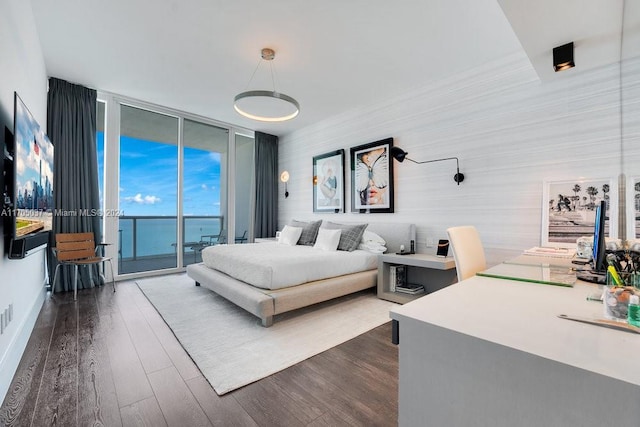 bedroom featuring access to exterior, a water view, dark hardwood / wood-style floors, and a wall of windows