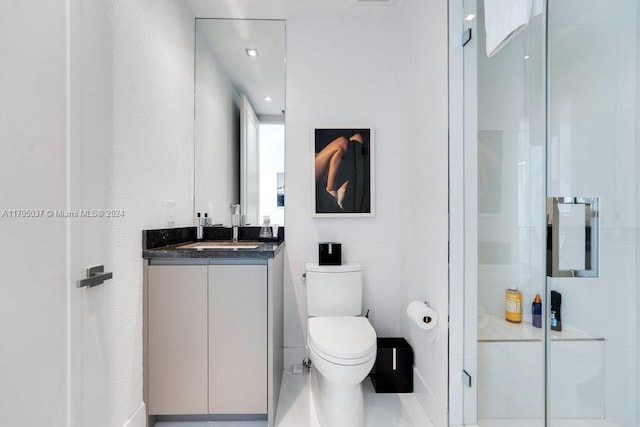 bathroom featuring tile patterned floors, vanity, toilet, and a shower with shower door