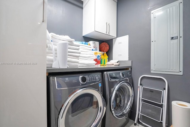 clothes washing area featuring cabinets, washing machine and dryer, and electric panel