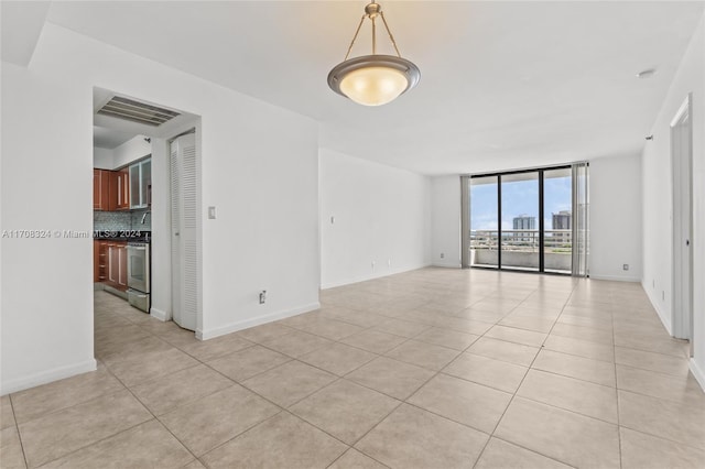 empty room featuring expansive windows and light tile patterned flooring