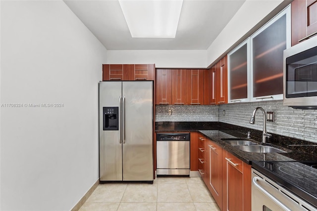 kitchen featuring dark stone counters, sink, decorative backsplash, appliances with stainless steel finishes, and light tile patterned flooring