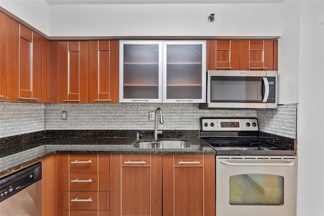 kitchen with decorative backsplash, sink, stainless steel appliances, and dark stone counters