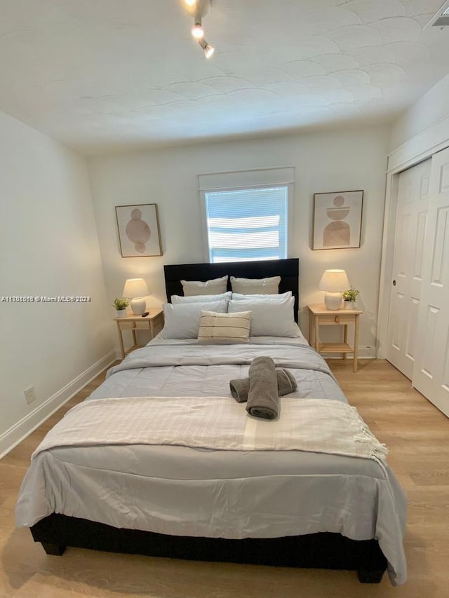 bedroom with light wood-type flooring and a closet