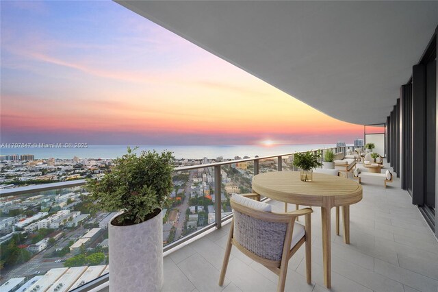 balcony at dusk featuring a water view