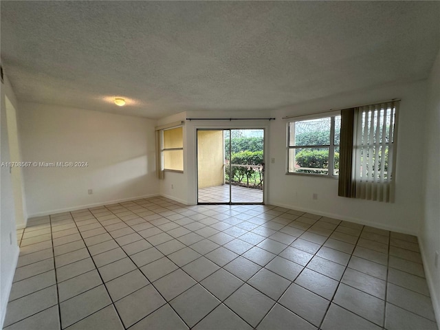 tiled spare room featuring a textured ceiling