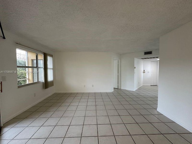 spare room featuring light tile patterned floors and a textured ceiling