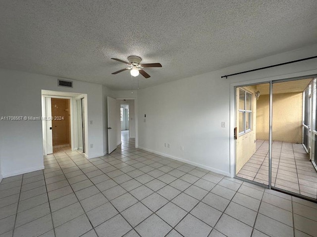 tiled empty room with ceiling fan and a textured ceiling