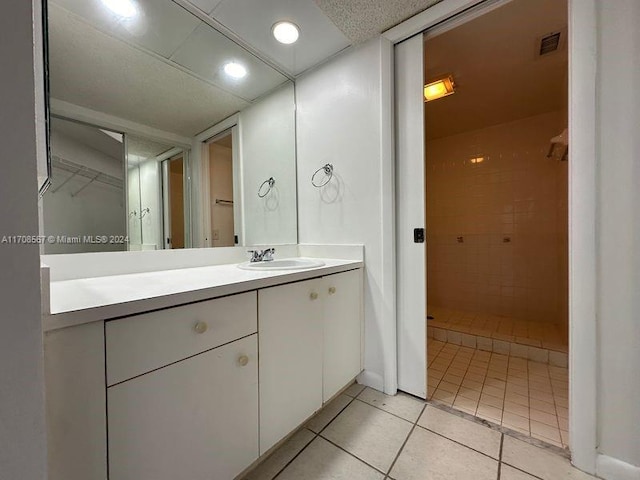 bathroom featuring tile patterned floors, vanity, and a tile shower