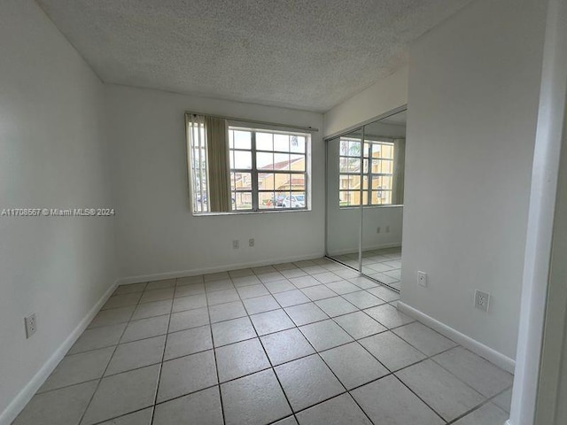 tiled empty room featuring a textured ceiling