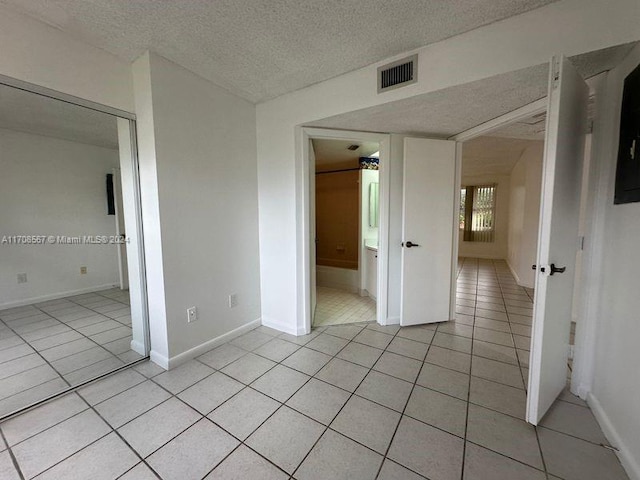 unfurnished bedroom featuring a closet, light tile patterned flooring, and a textured ceiling