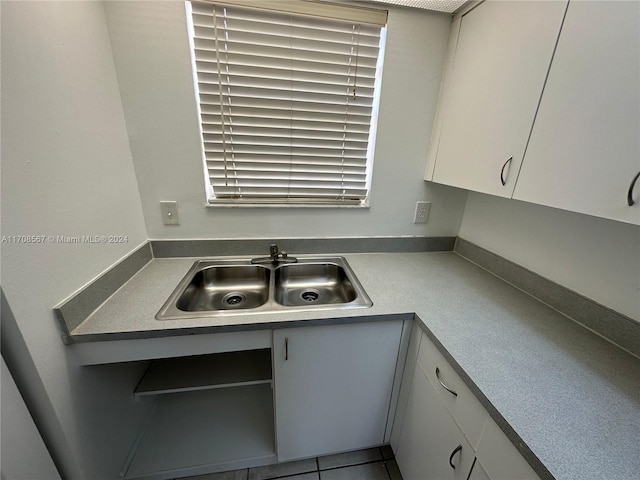 kitchen with tile patterned floors, white cabinetry, and sink