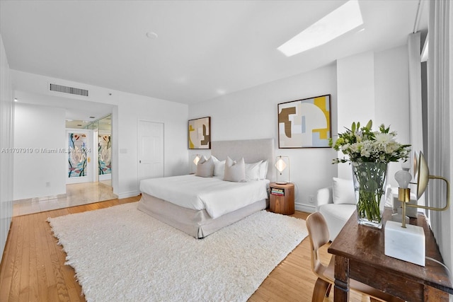 bedroom with a skylight, a closet, and hardwood / wood-style flooring