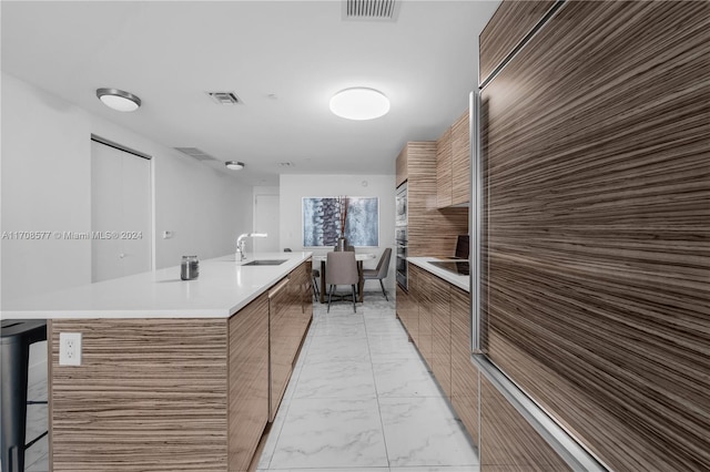 kitchen featuring sink, an island with sink, and stainless steel appliances