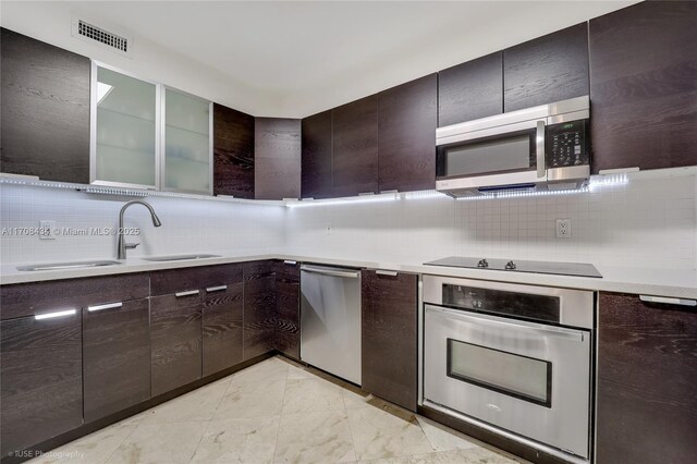 kitchen featuring appliances with stainless steel finishes, dark brown cabinetry, tasteful backsplash, and sink