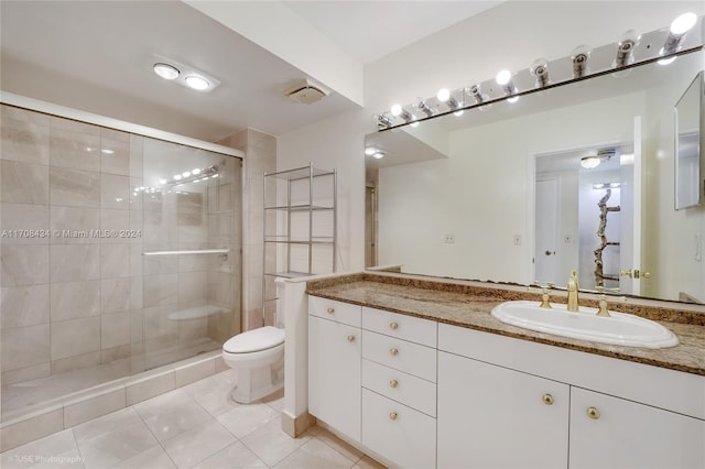 bathroom with tile patterned floors, vanity, an enclosed shower, and toilet