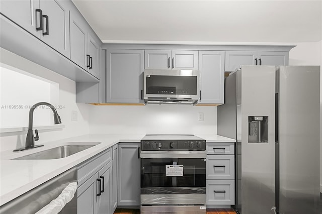 kitchen with stainless steel appliances, gray cabinetry, and sink