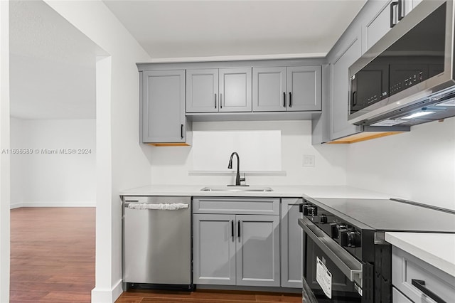 kitchen with gray cabinetry, stainless steel appliances, dark wood-type flooring, and sink