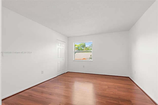 unfurnished room with hardwood / wood-style floors and a textured ceiling