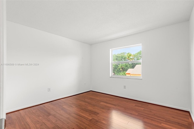 unfurnished room with hardwood / wood-style floors and a textured ceiling